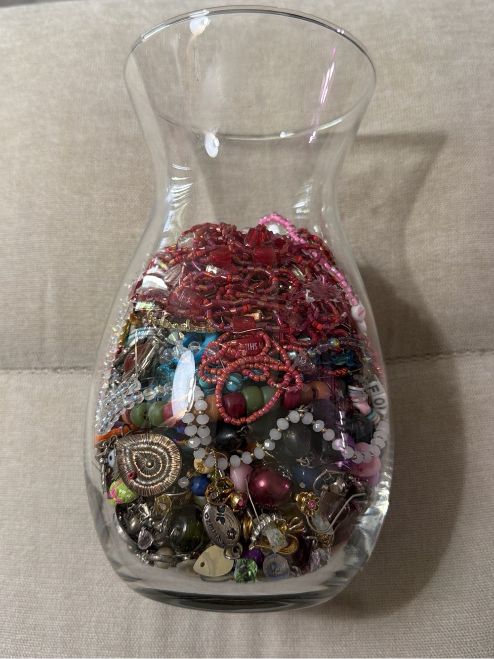 Clear Glass Vase Filled With Colorful Beads and Jewelry Accents